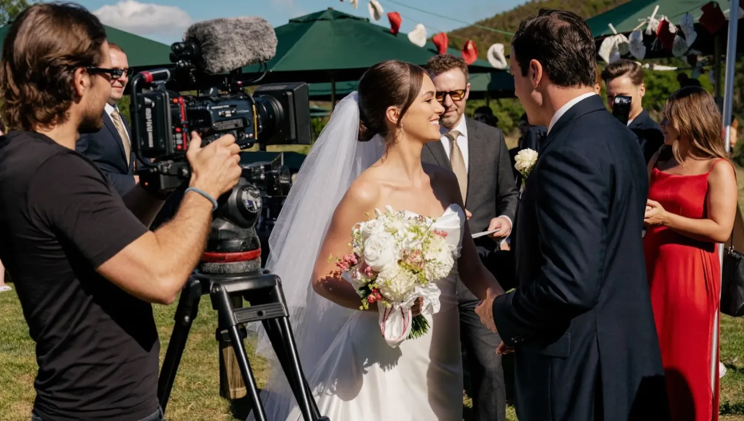 Vidéaste avec sa caméra filmant un mariage en plein air